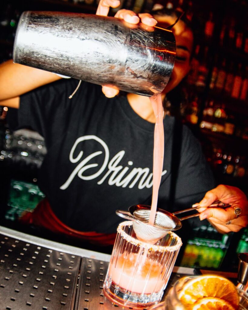 Bartender de Primo sirviendo un cóctel desde la coctelera en la barra de Primo Madrid