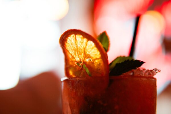 Cóctel con rodaja de naranja deshidratada y hierbabuena en la barra de Primo, coctelería mexicana junto a Sol