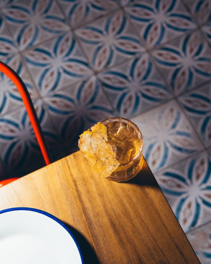 Vaso corto con hielo sobre la barra de madera y el suelo de baldosa de Primo Madrid